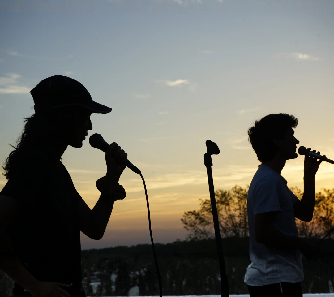 Blaise et Nico chantant sur scène au coucher du soleil lors d'un concert
